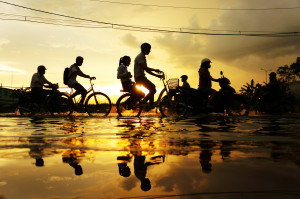 HO CHI MINH CITY, VIET NAM- OCT 9: Amazing scene of Ho Chi Minh city when flood tide, street flooded, silhouette of people riding motorbike, bike in water at sunset, yellow sun, Vietnam, Oct 9, 2014